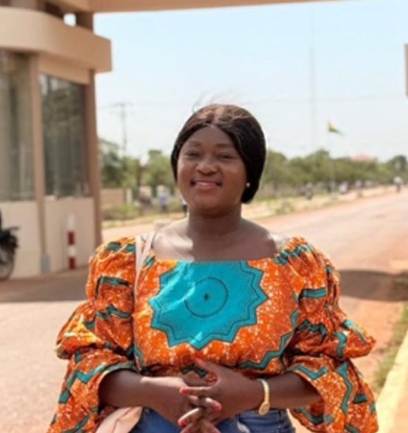 An image of Tina standing and smiling at the camera while undertaking her field work.